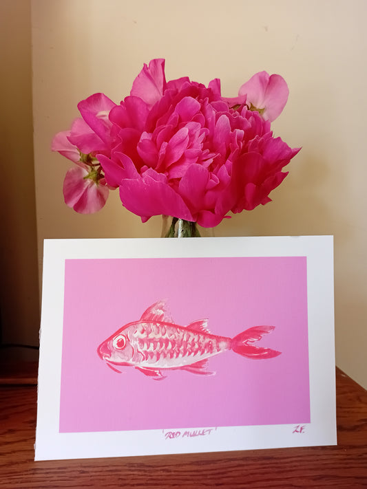 Art Print with pink fish illustration next to a pink flower on a wooden surface